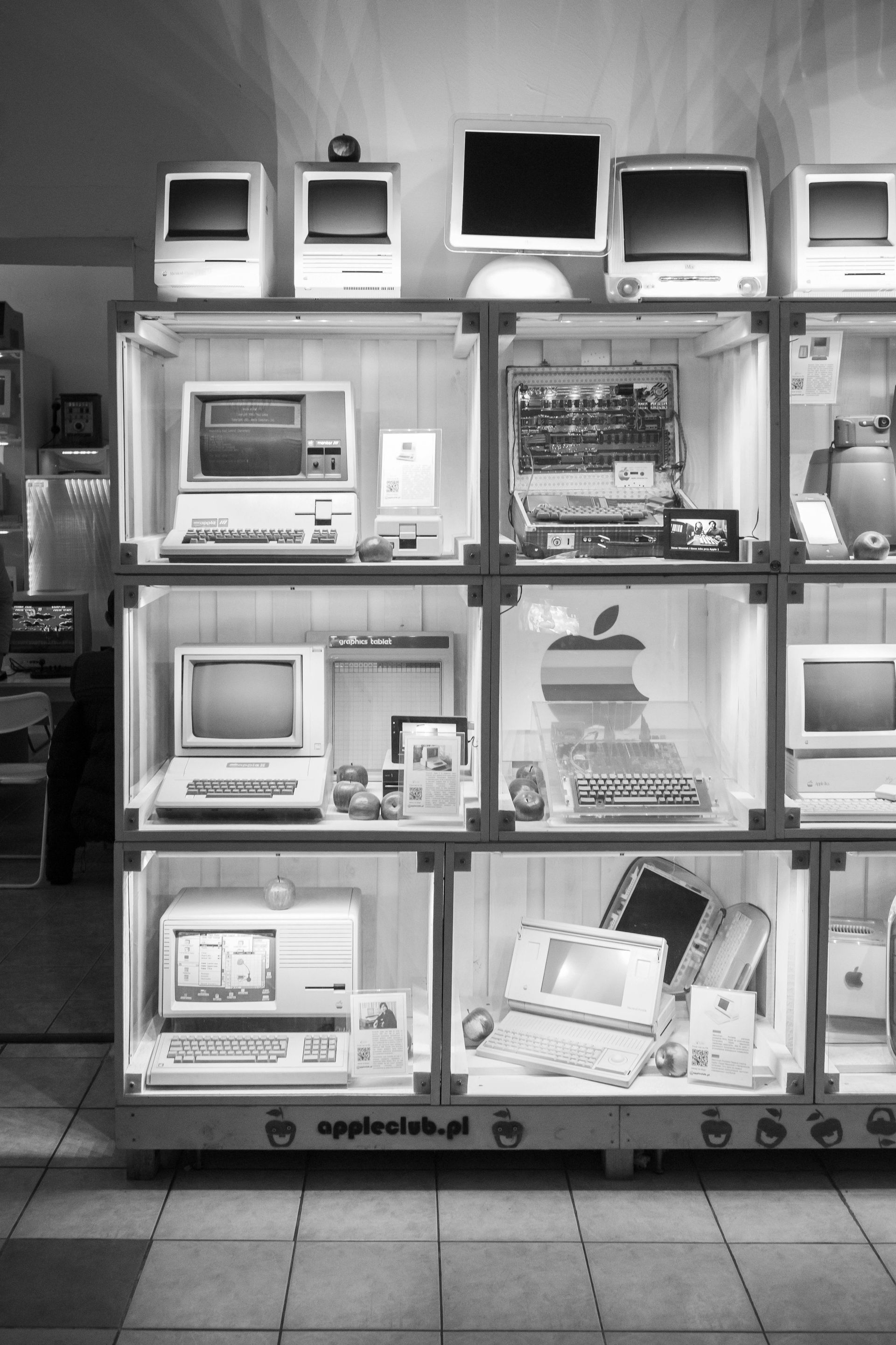 Black-and-white display of vintage Apple computers and accessories in a store window.
