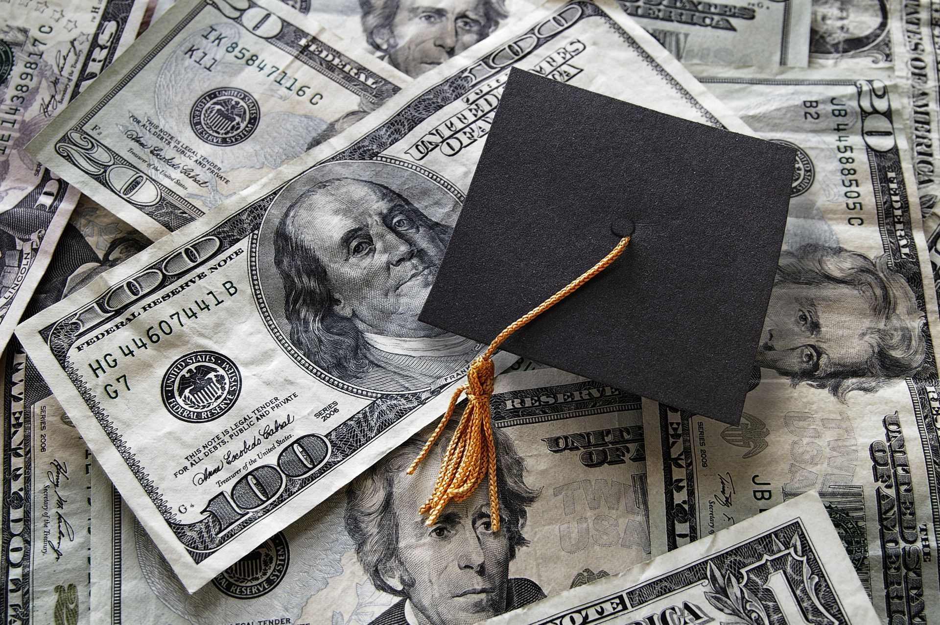 Graduation cap on a pile of $100 bills.