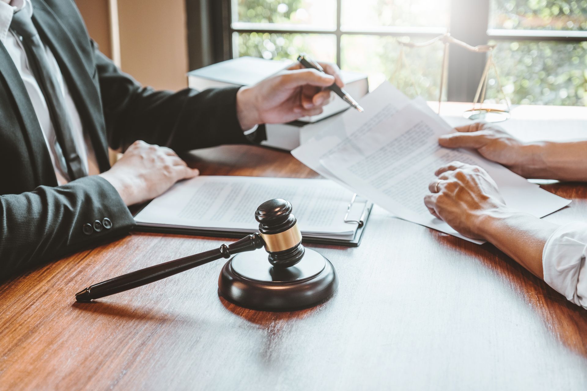 Lawyer pointing at document for client; gavel on desk.