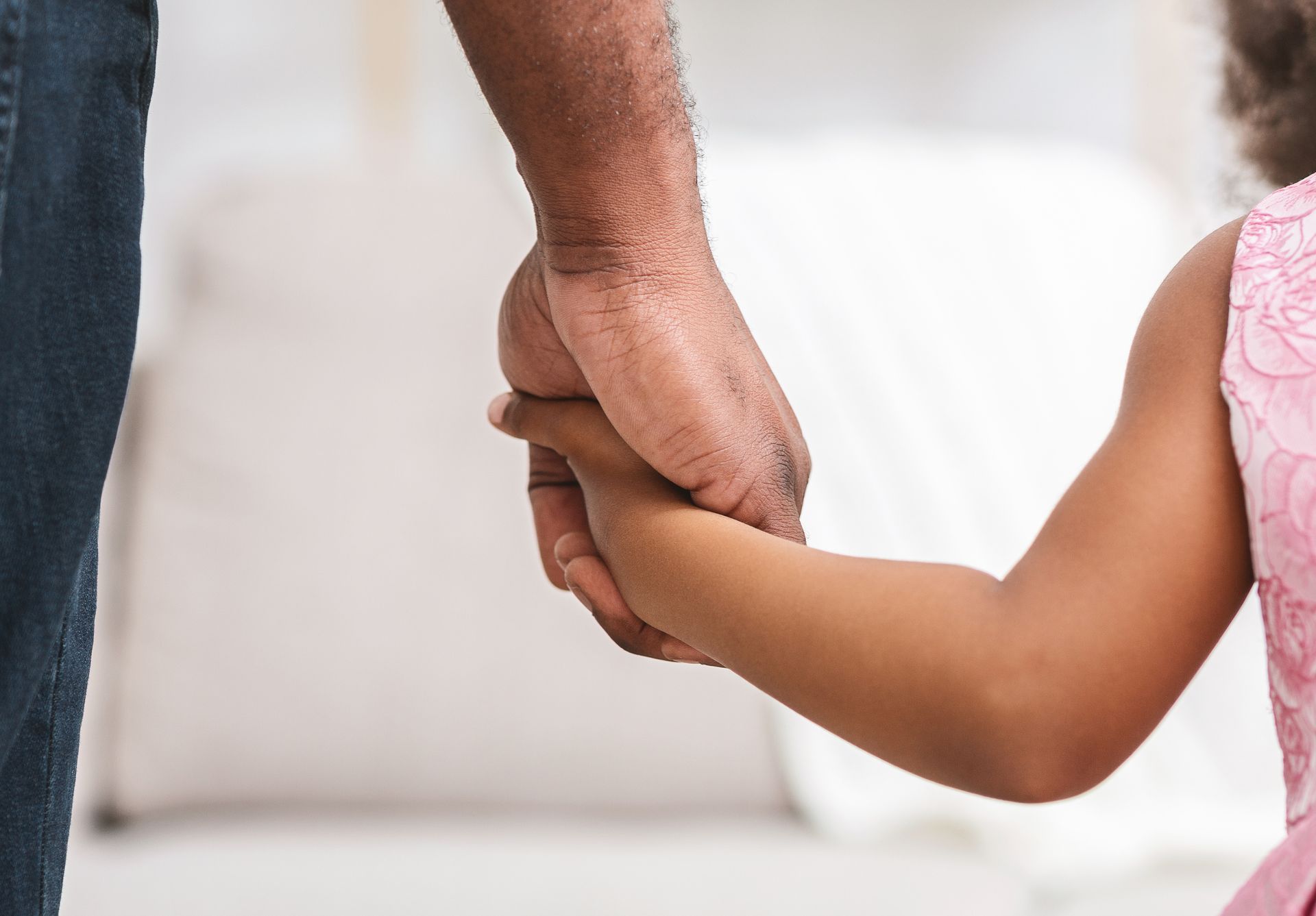 Adult hand holding a child's hand. Focus on hands, background blurred.