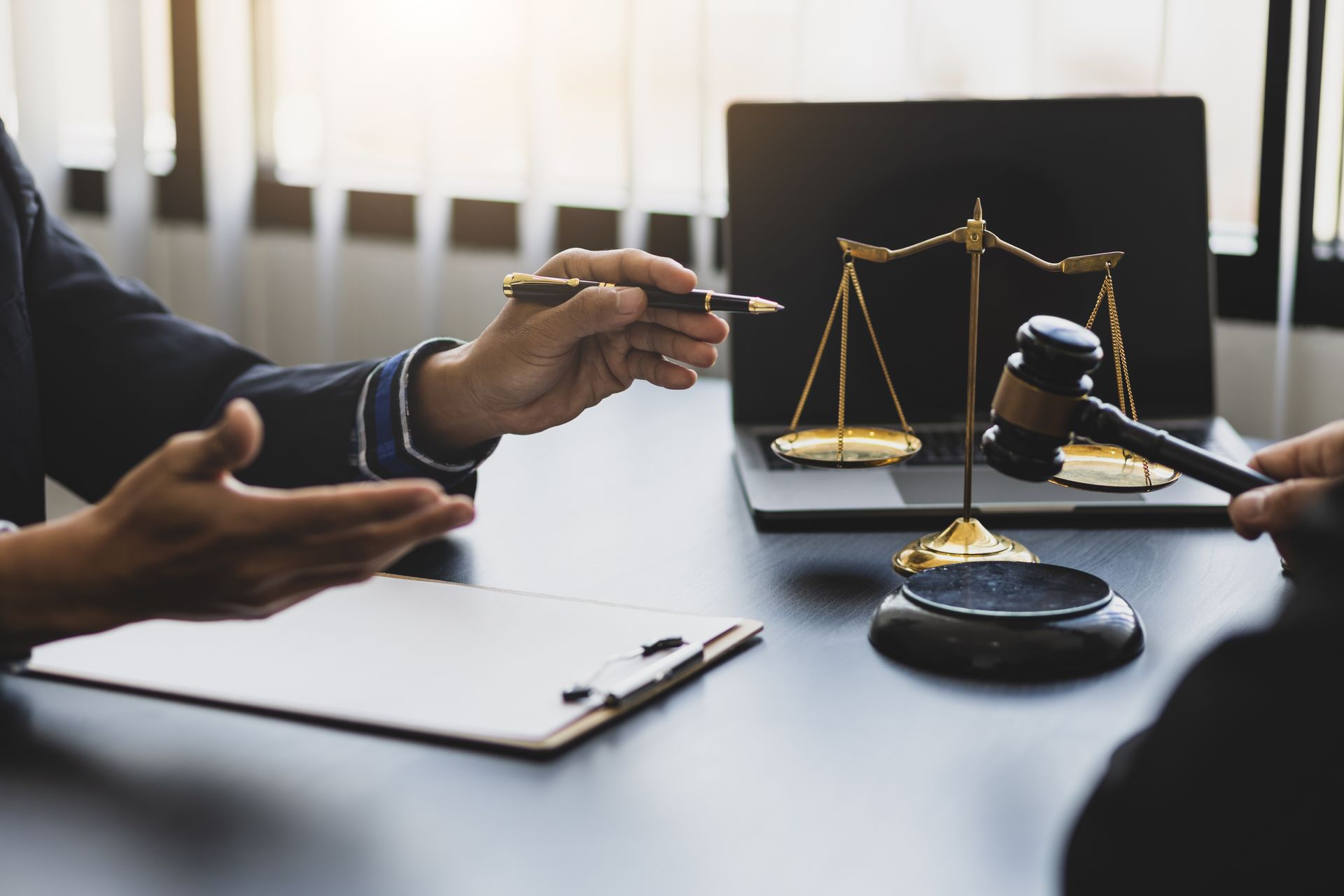 Lawyer’s desk with scales of justice, gavel, and two people discussing a case