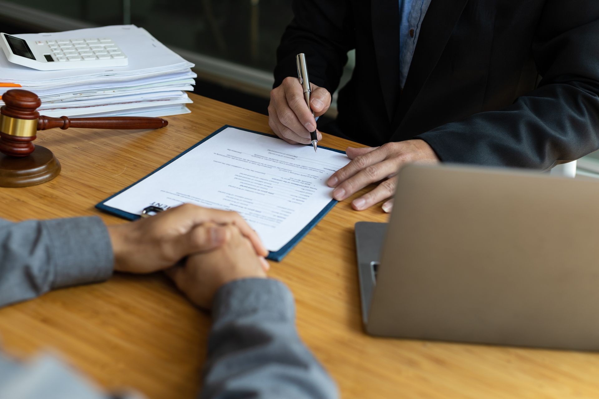 Bankruptcy attorney reviewing legal documents with a client at a law office desk with a gavel and financial paperwork Bankruptcy attorney reviewing legal documents with a client at a law office desk with a gavel and financial paperwork