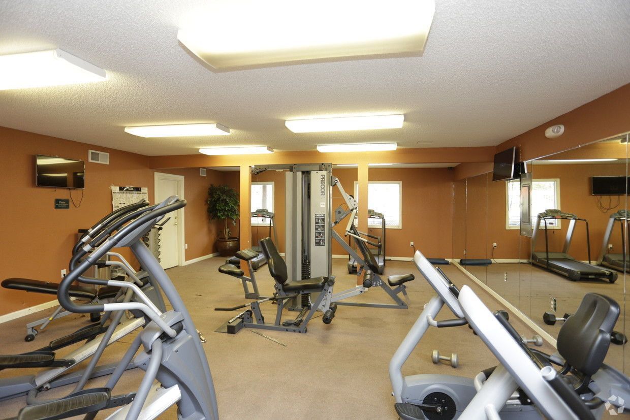 Gym interior with exercise machines, mirrors, and televisions.