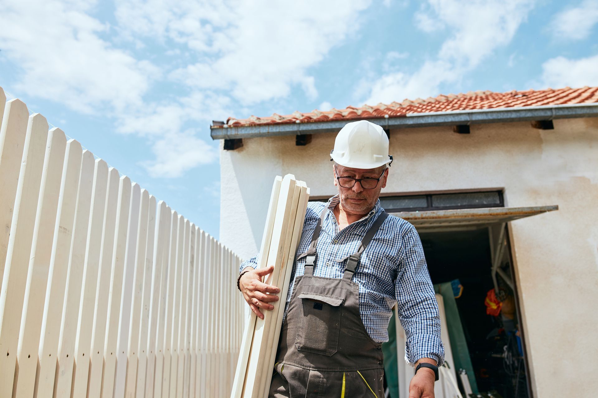 A man carrying a wooden fence panel, showcasing the work of local fence contractors in action.
