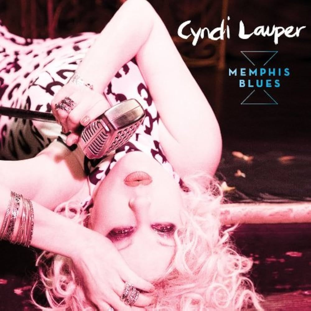 Cyndi Lauper lying down, holding a vintage microphone, album cover for