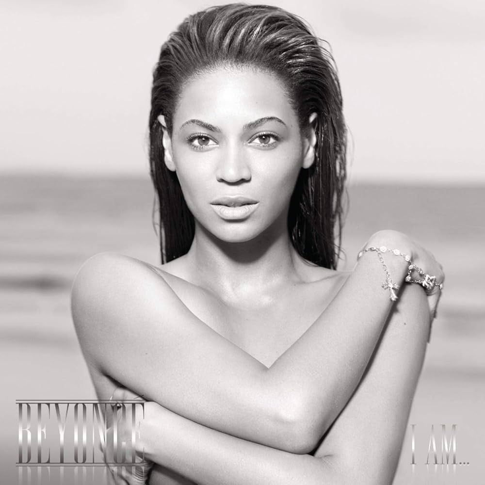 Beyoncé on a beach, in black and white, arms crossed. Album cover for
