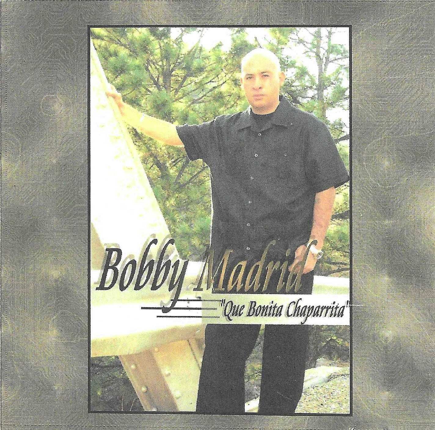 Album cover featuring Bobby Madrid, a bald man in a black shirt, leaning on a structure outdoors. Title: