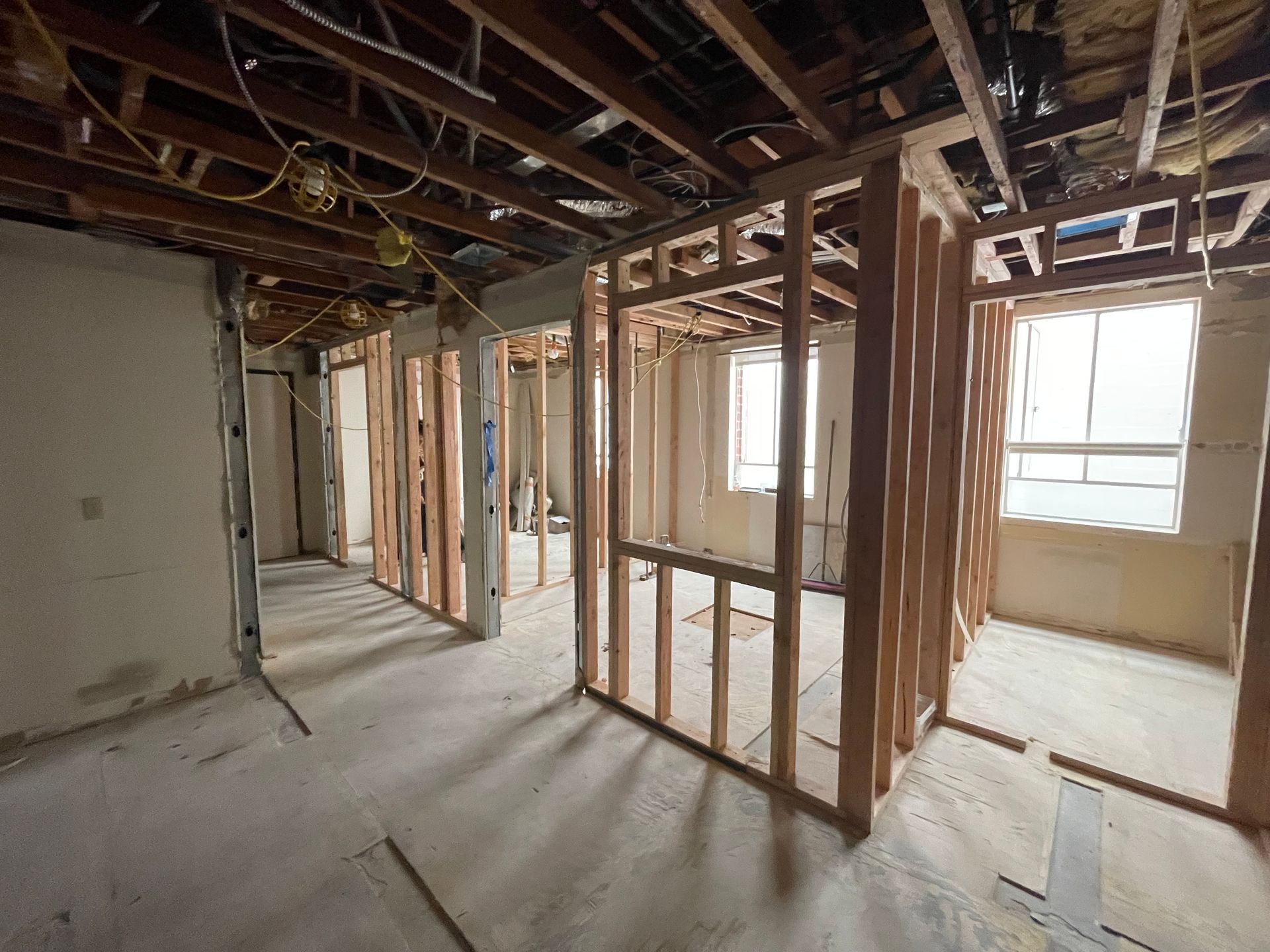 Interior under renovation with exposed studs, unfinished ceiling, and daylight through windows