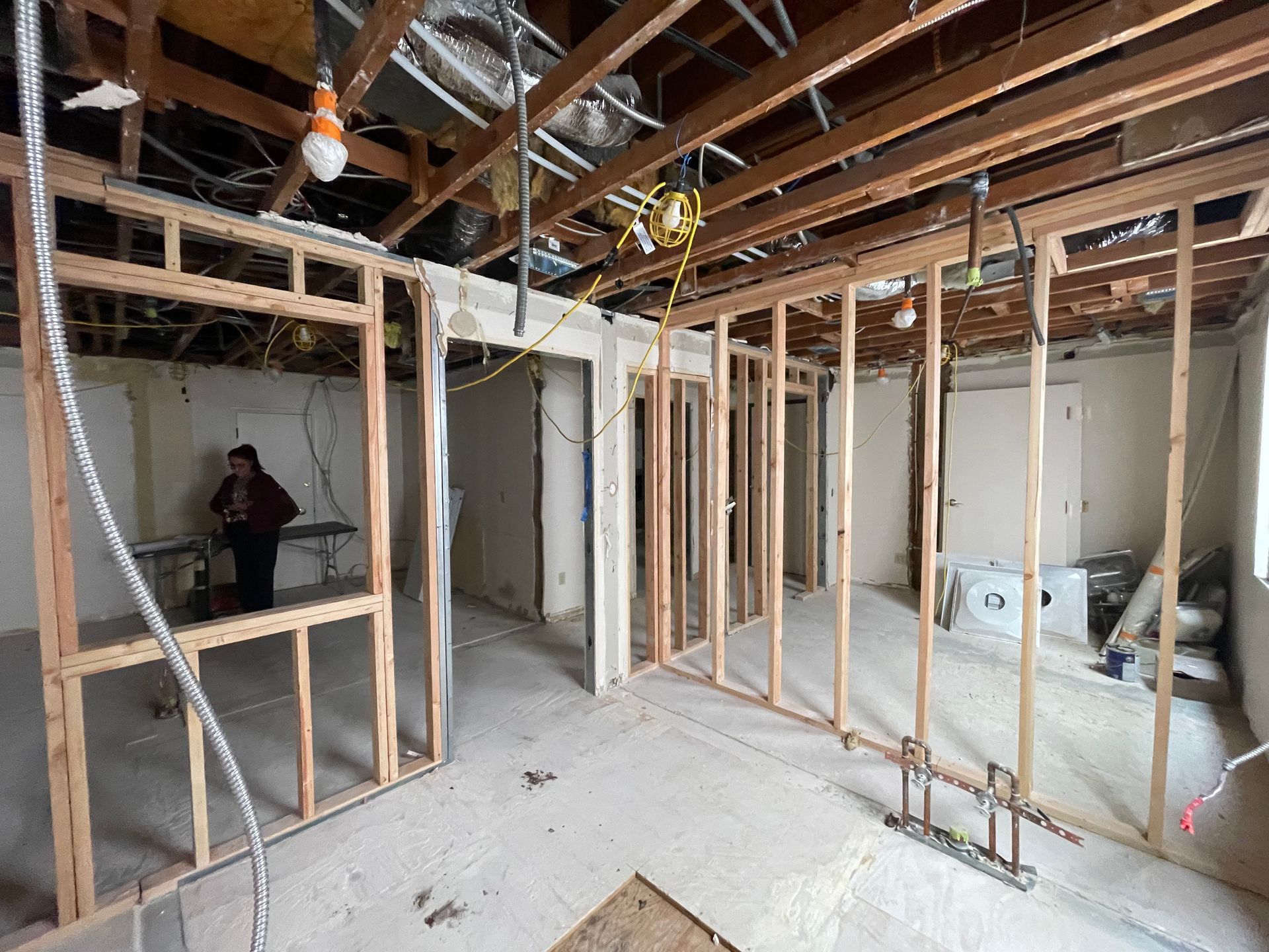 Interior under renovation with exposed wooden framing, ceiling beams, and construction materials on the floor.