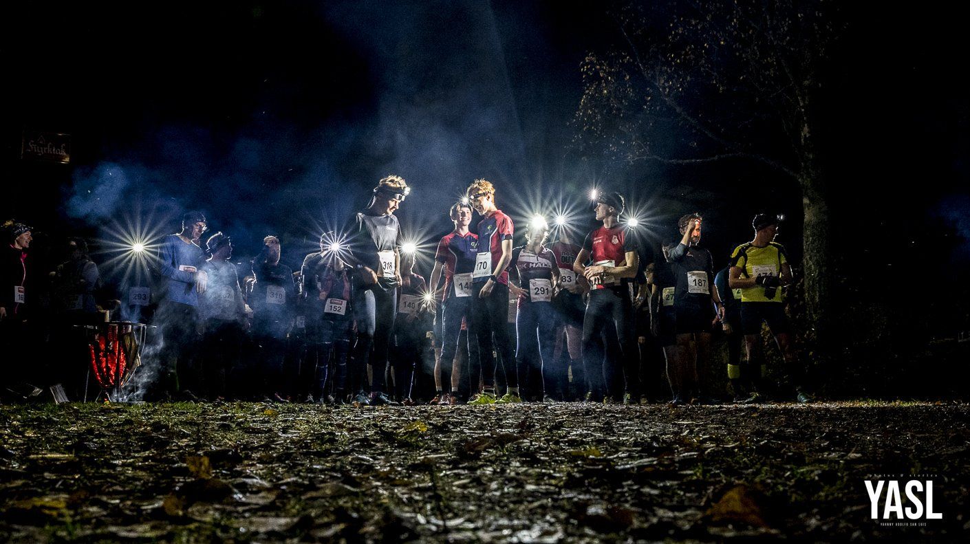 A group of people are running in the dark with flashlights.