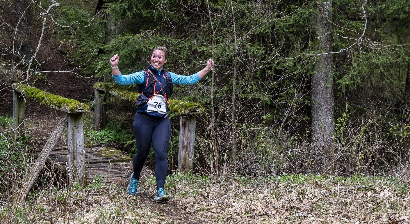A woman is running through a forest on a trail.