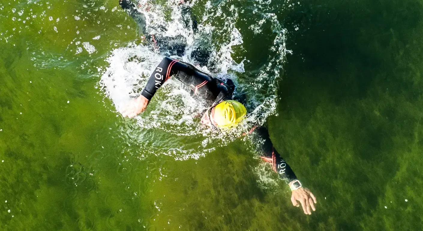 An aerial view of a person swimming in a lake.