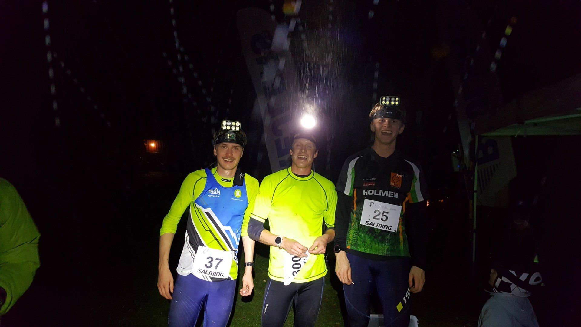 Three men are standing next to each other in the dark.