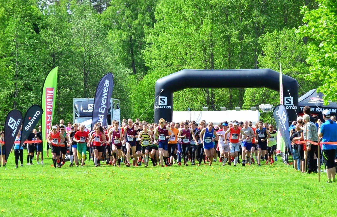 A large group of people are running a race in a park.