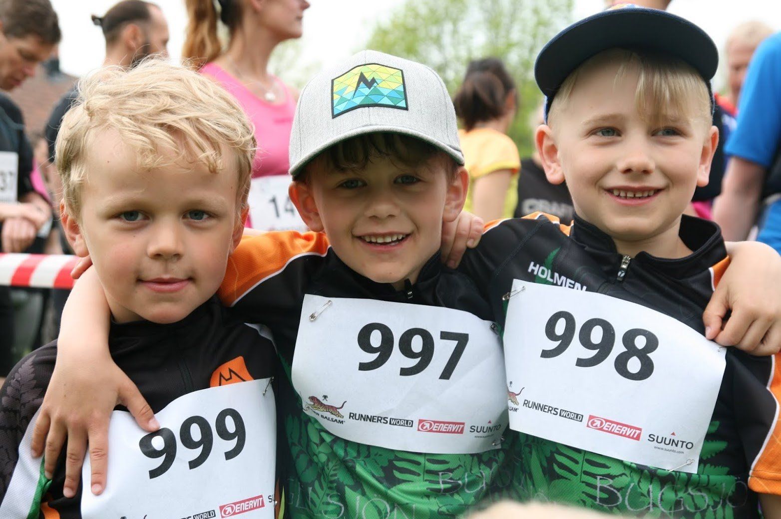Three young boys wearing numbers 997 and 998 are posing for a picture