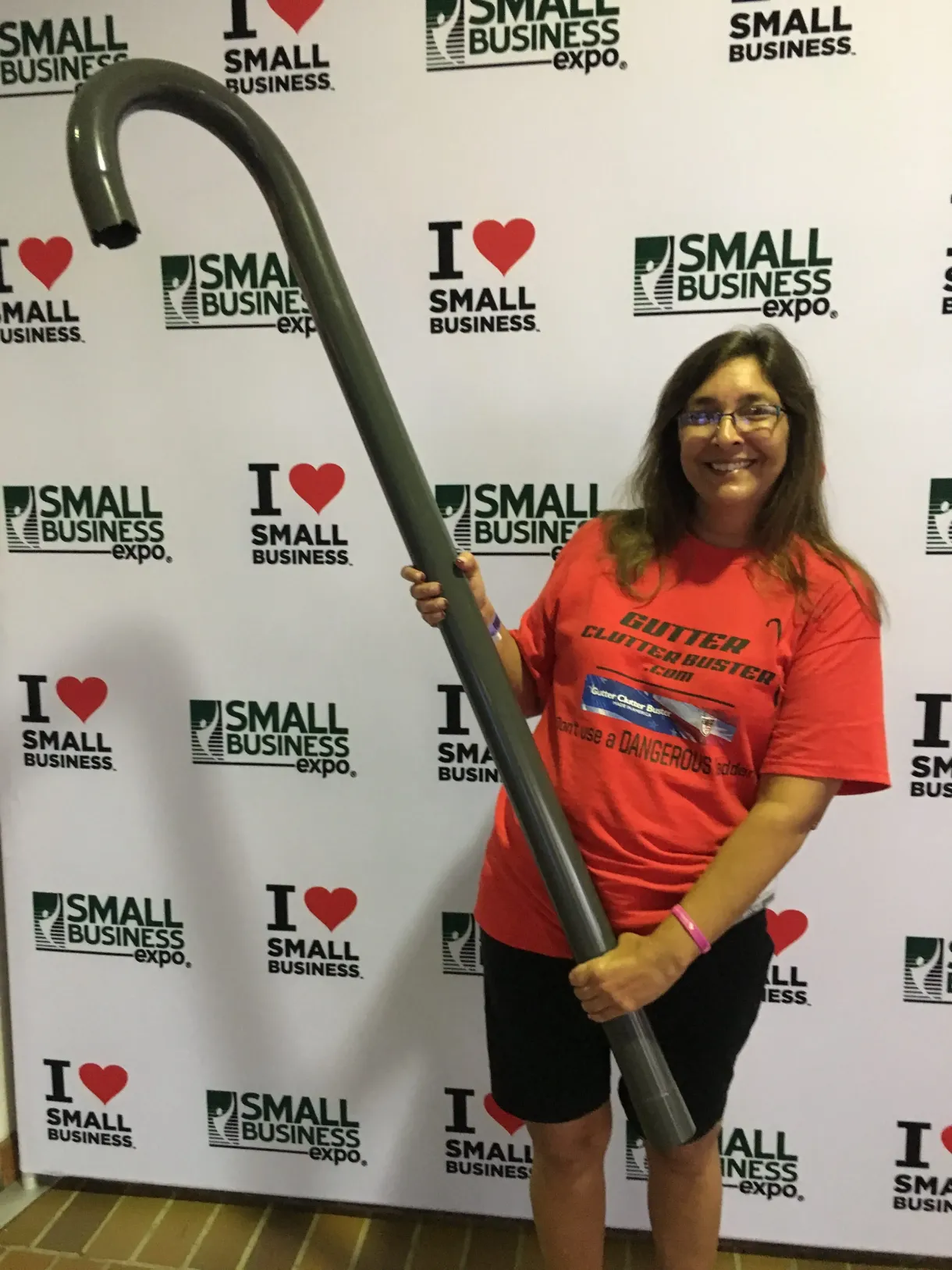 A woman in a red shirt is holding a large cane