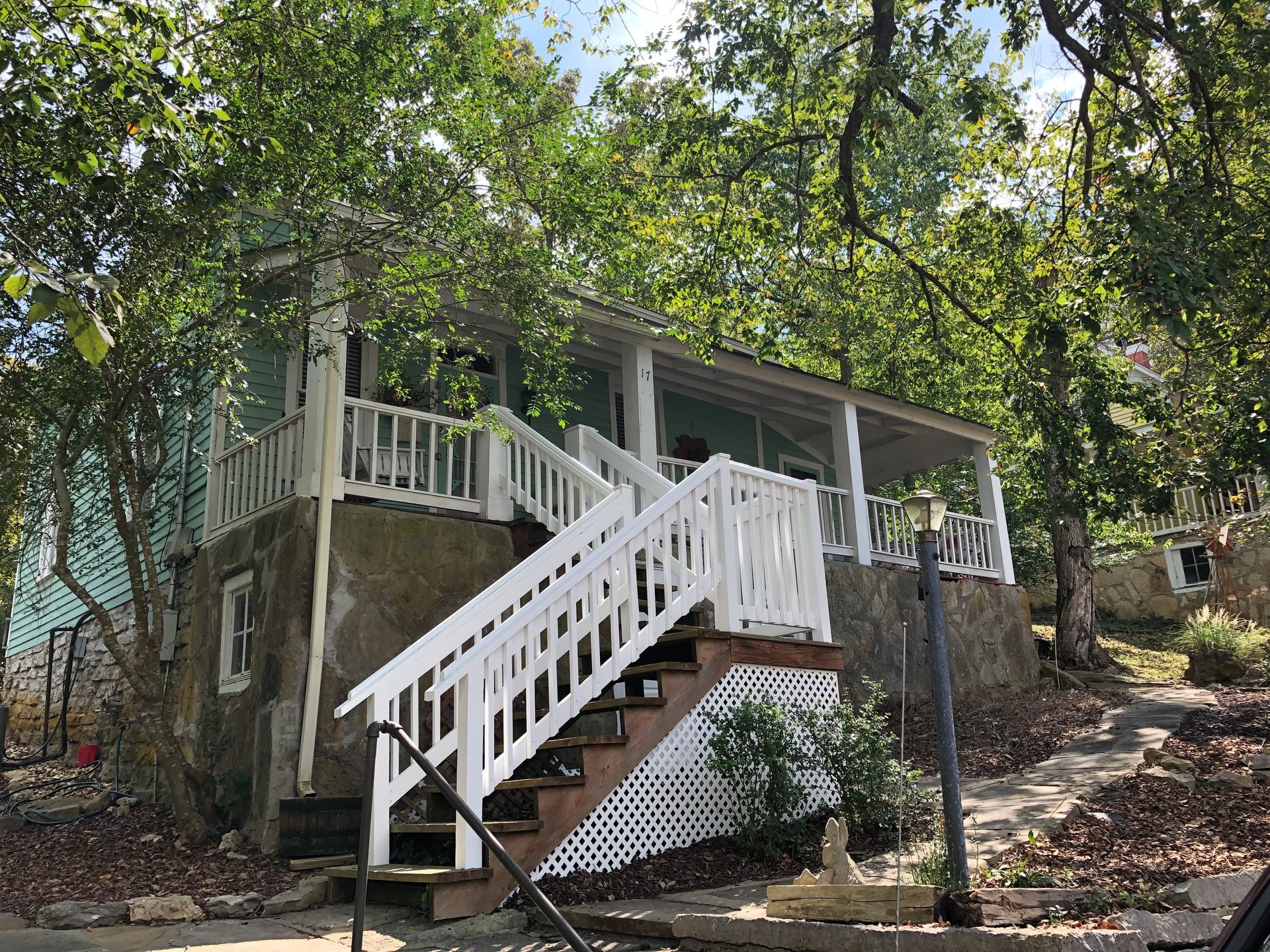 A small house with stairs leading up to a porch surrounded by trees.