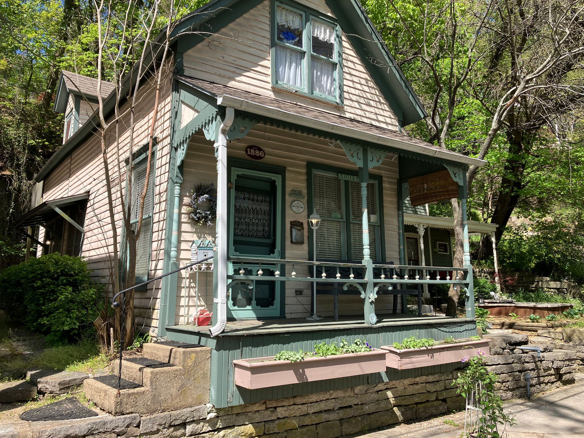 A small house with a porch is surrounded by trees.