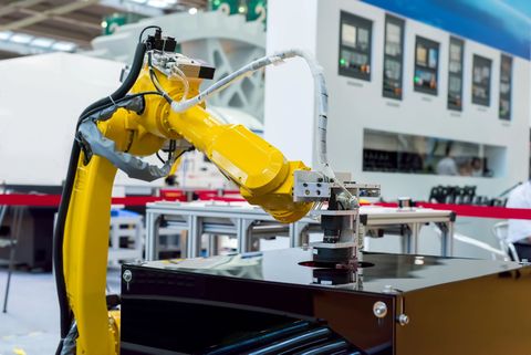 Primo piano di macchinari industriali con componenti in metallo argentato, tubi blu e connettori gialli.