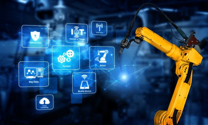 Braccio robotico giallo con icone digitali in un ambiente di produzione.