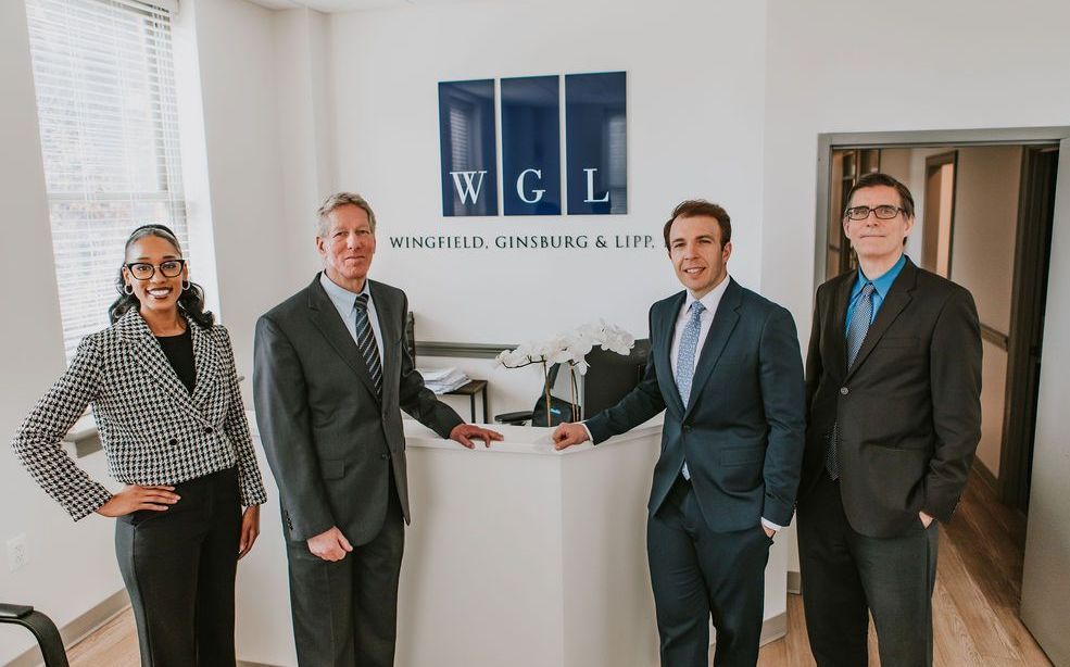 A group of people in suits and ties are standing in front of a wgl sign.