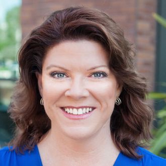 A woman in a blue shirt is smiling for the camera.