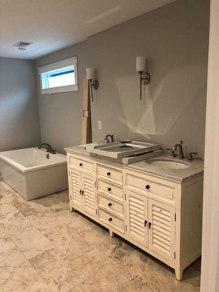Bathroom with a freestanding tub, double vanity, and marble tile floor.
