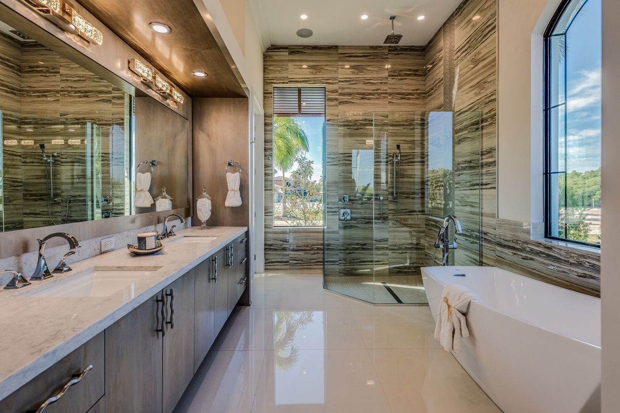 Modern bathroom with double vanity, glass shower, freestanding tub, and large windows