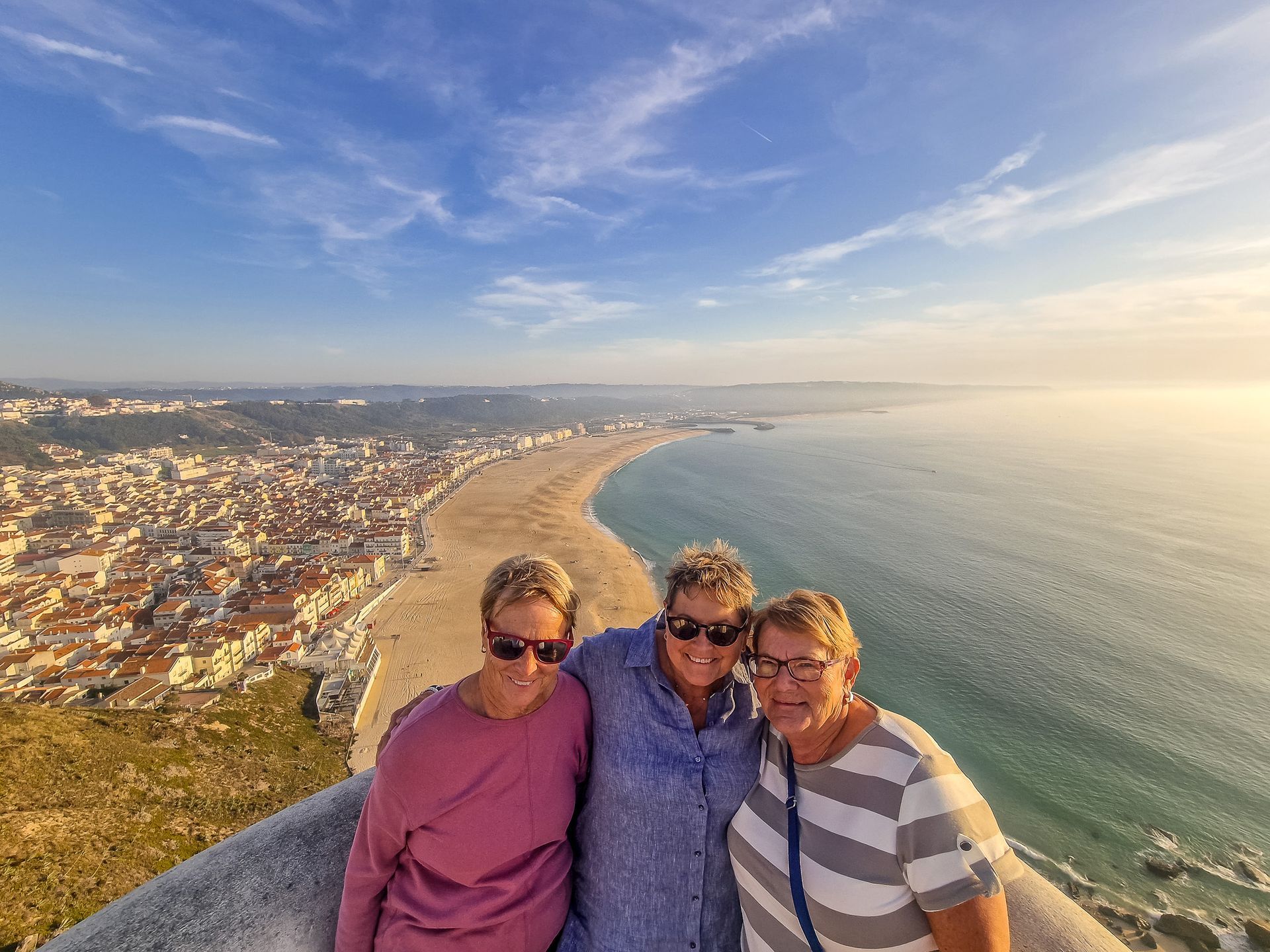 3 happy ladies in Sitio in Nazare with the Ocean on their back during a transfer from Lisbon to Porto with Duca