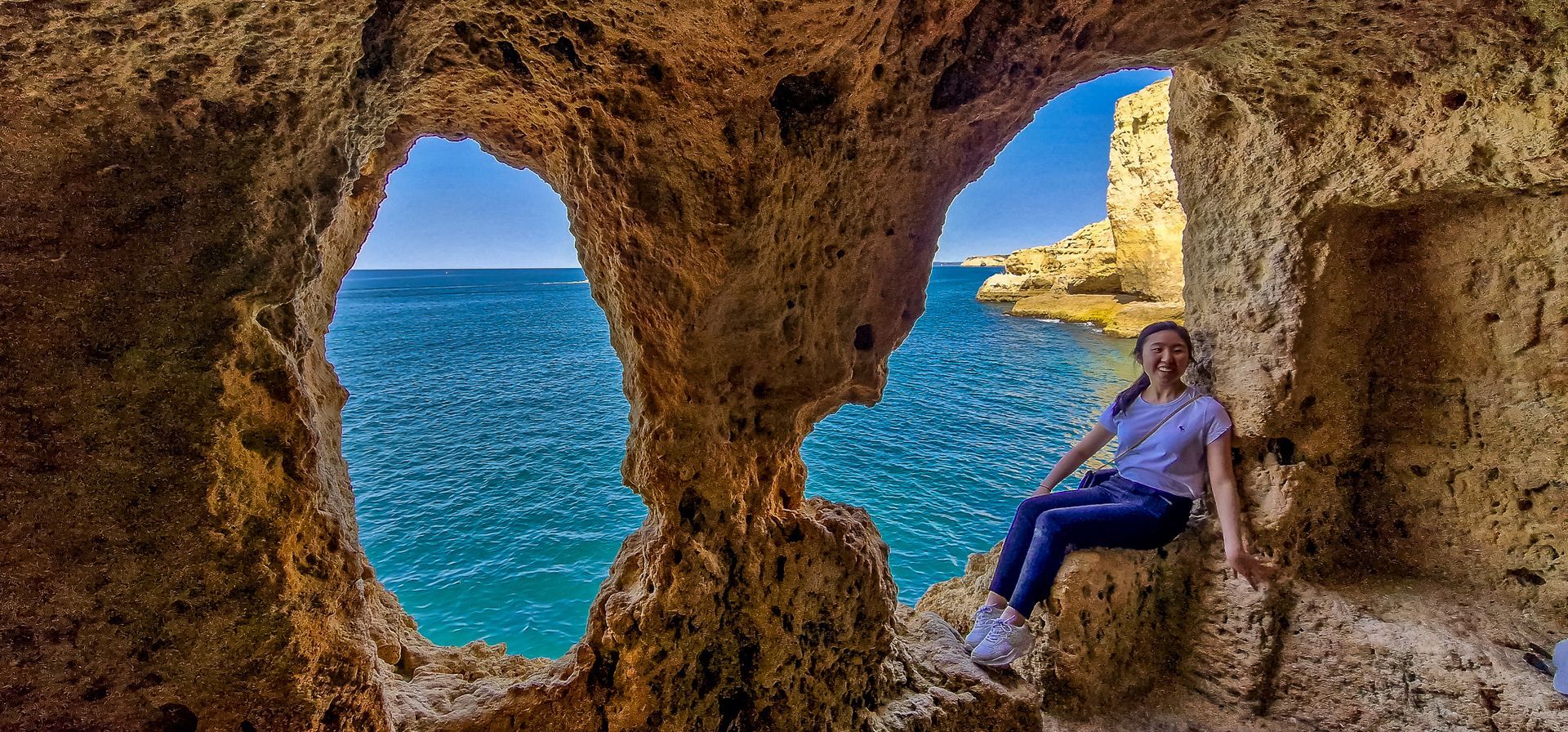 A young girl exploring the inside of A Boneca cave in Algar Seco, Carvoeiro, standing by the two ico