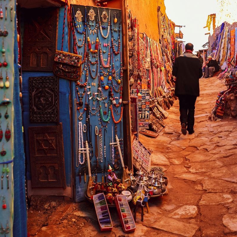 A man in a black suit walks down a cobblestone street
