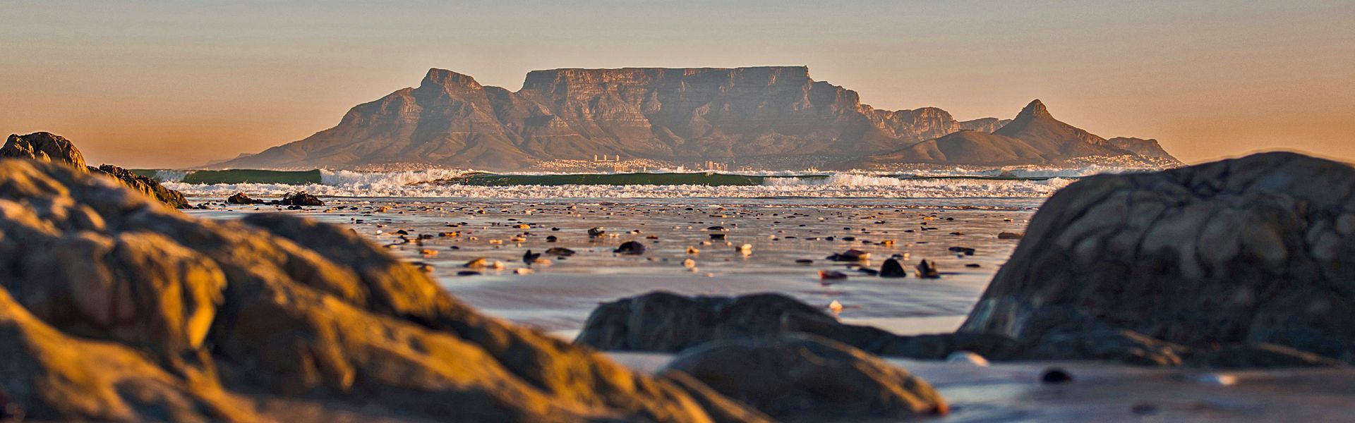 Discover Cape Town’s iconic Table Mountain on a clear day, framed by ocean waves. Expertly curated South Africa journeys by Belafrique and Africa DMCs.