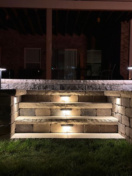 A set of outdoor stone steps at night, illuminated by soft, integrated LED lights built into each stair riser.