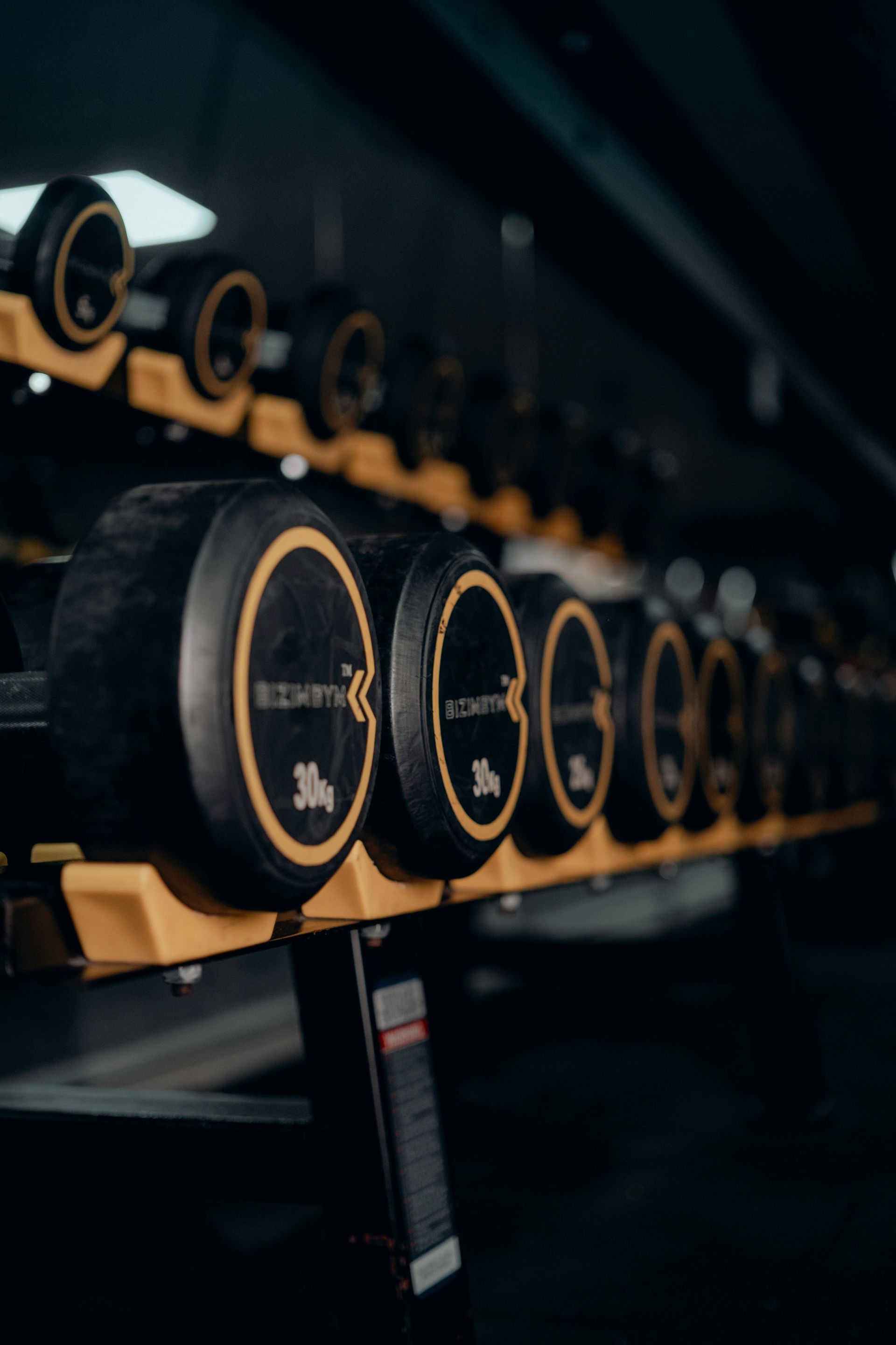 Een vrouw en een man glimlachen terwijl ze op een crosstrainer trainen in een sportschool met paarse accentverlichting.