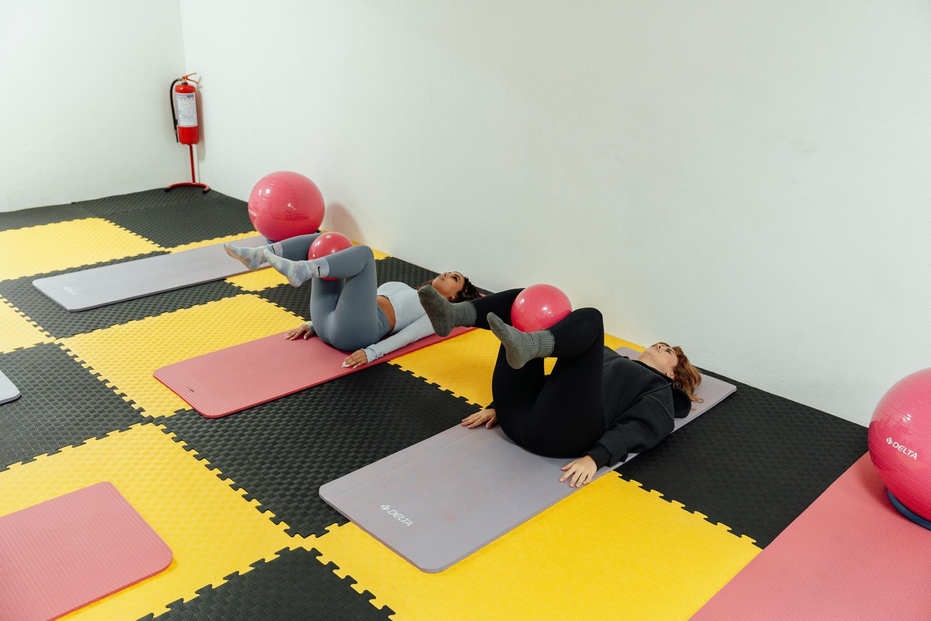 Vrouw die halter squats doet in een sportschool, gekleed in een felgroen shirt en een zwarte legging.