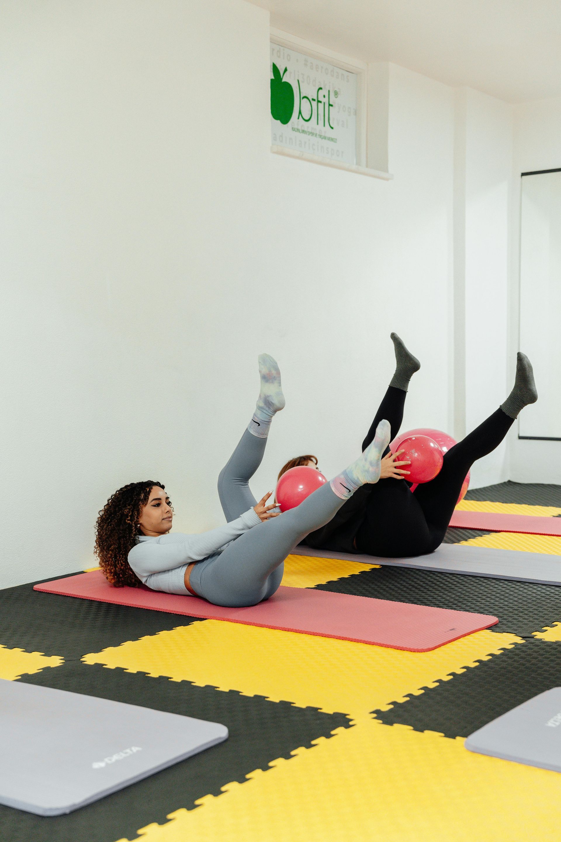 Vrouw die halter squats doet in een sportschool, gekleed in een felgroen shirt en een zwarte legging.
