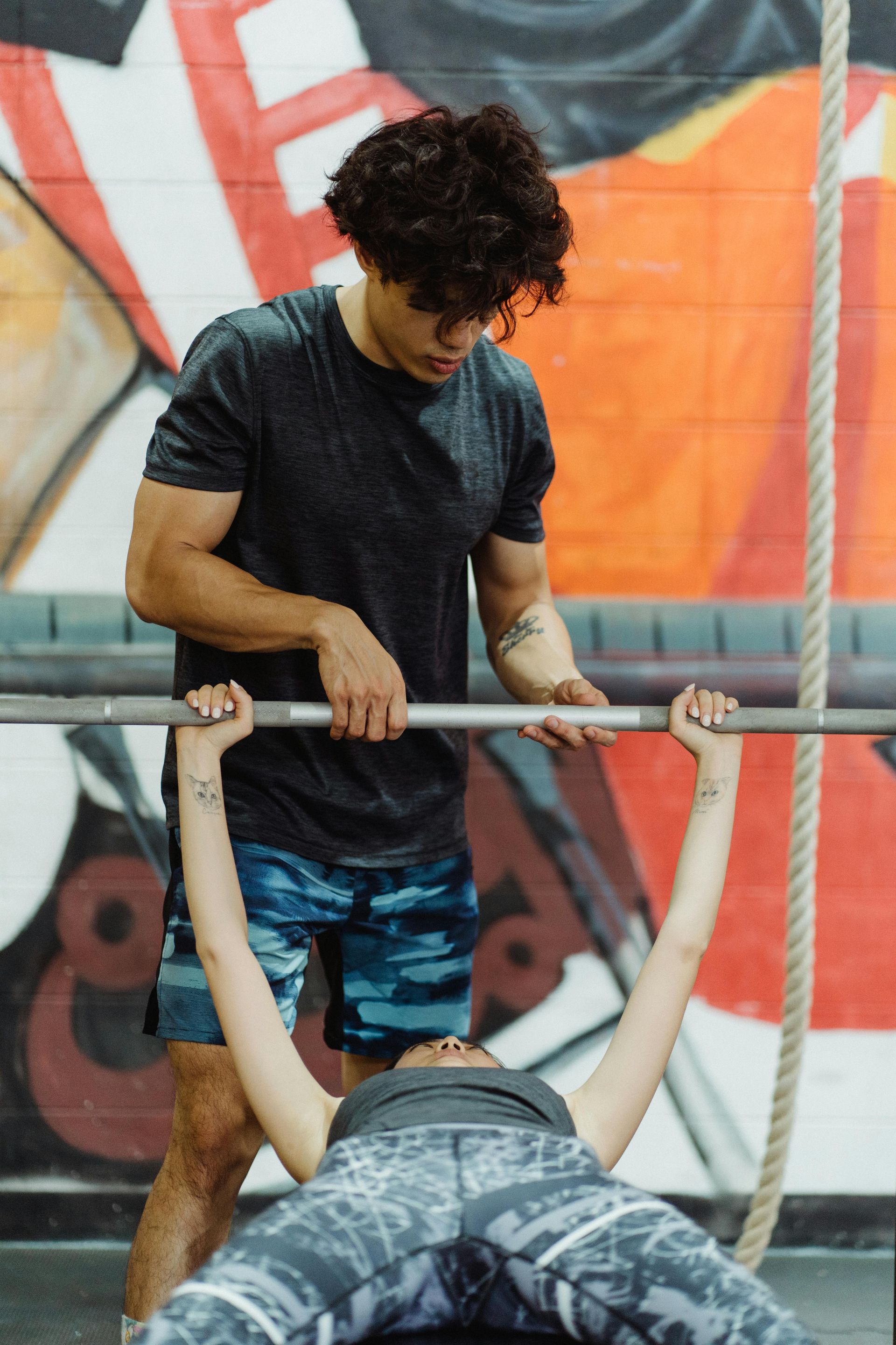 Een man doet dumbbell chest press met een spotter in een sportschool.