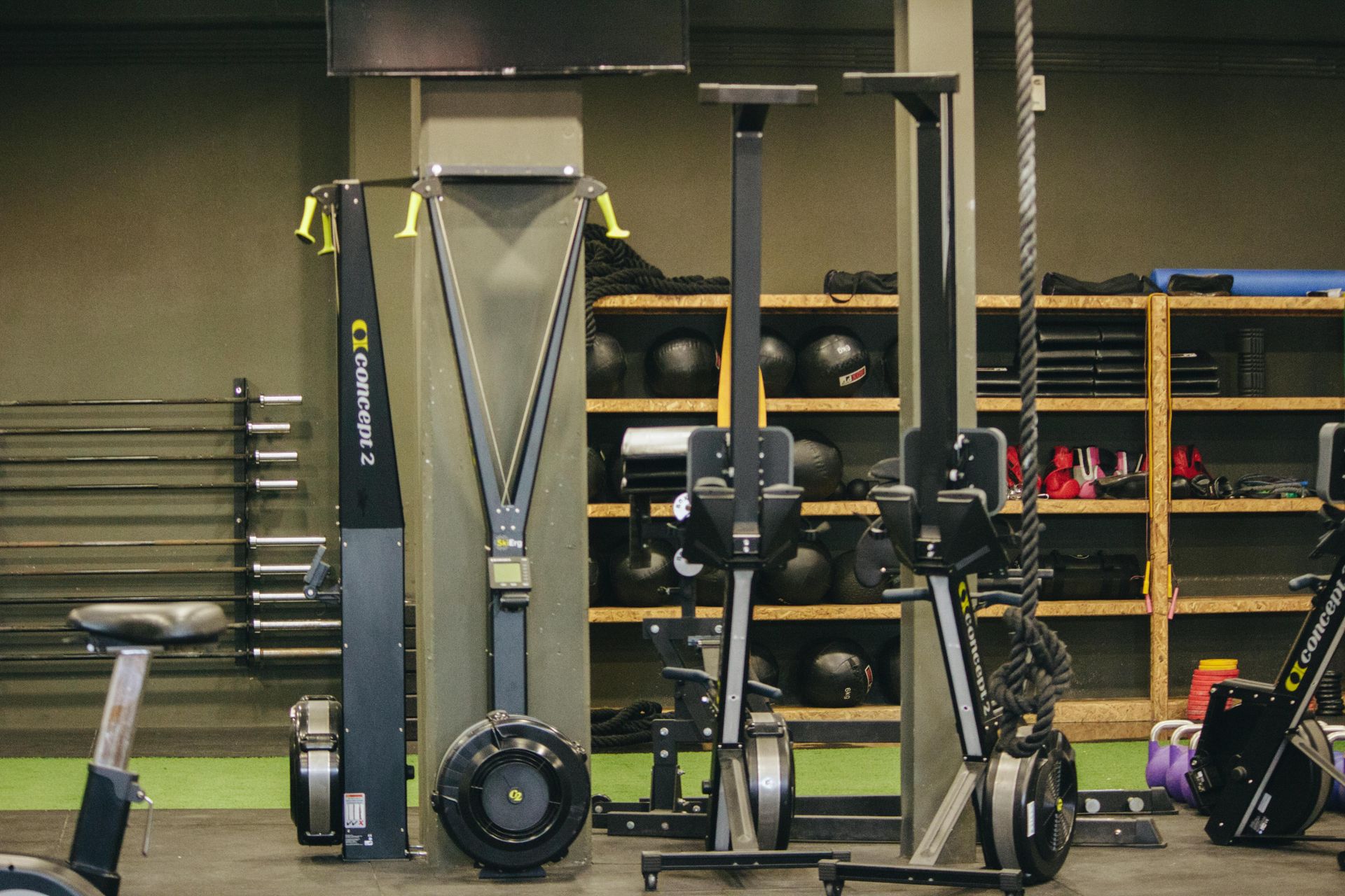 Fitnessapparatuur en halters opgesteld in een gewichtsruimte met planken op de achtergrond.