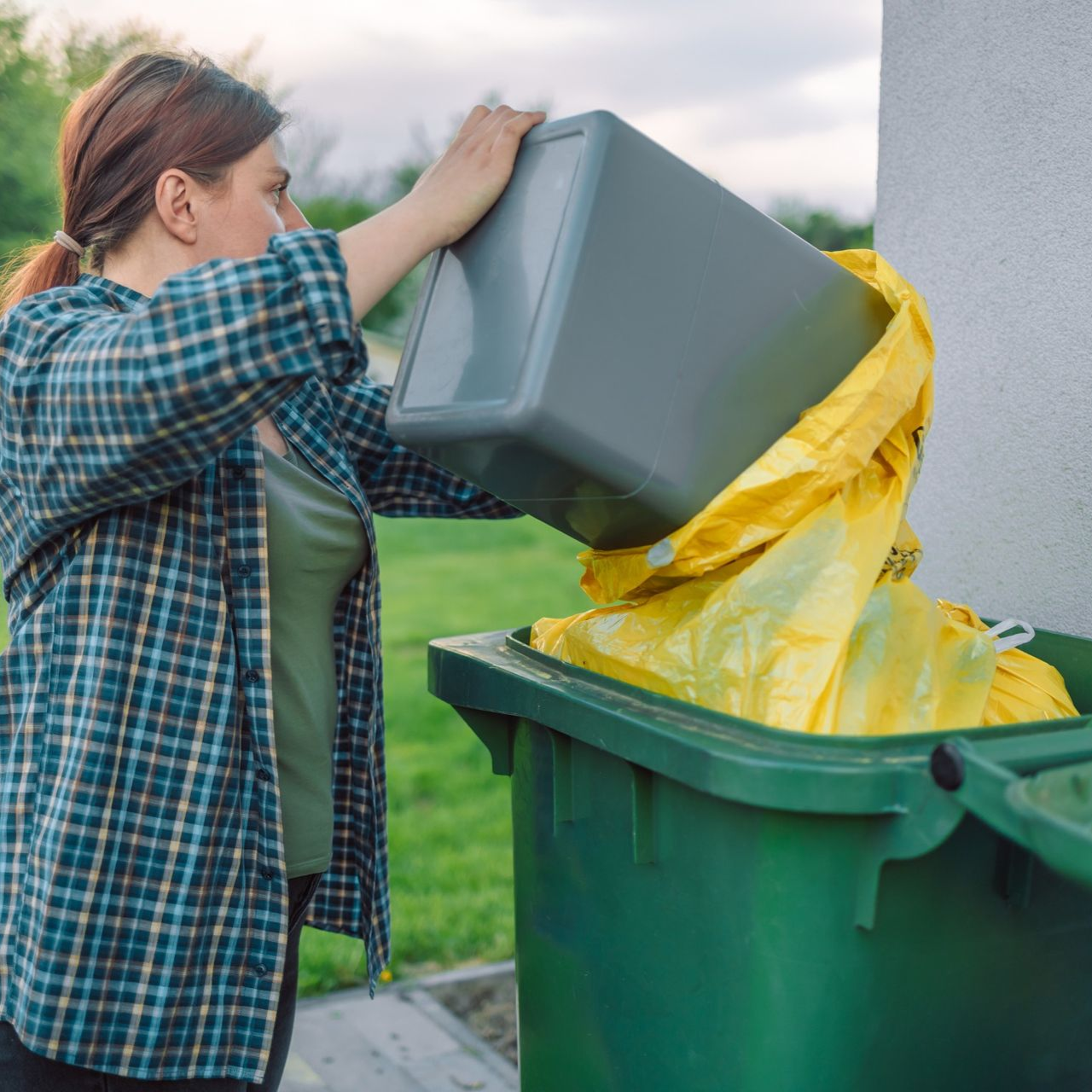 A green trash can with a piece of paper in it.