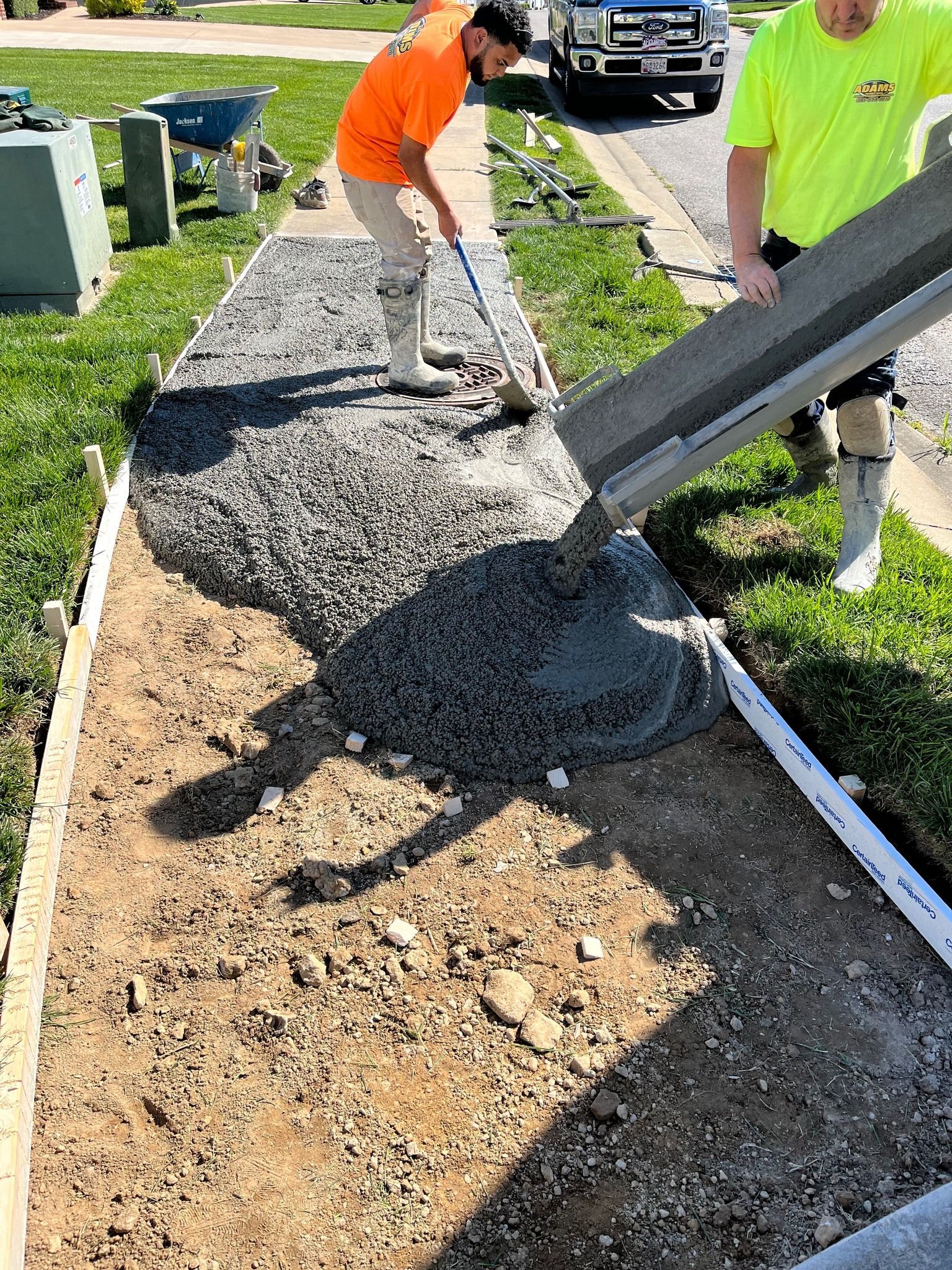 Adams Property works, pour wet concrete onto a prepared gravel path outside a home.