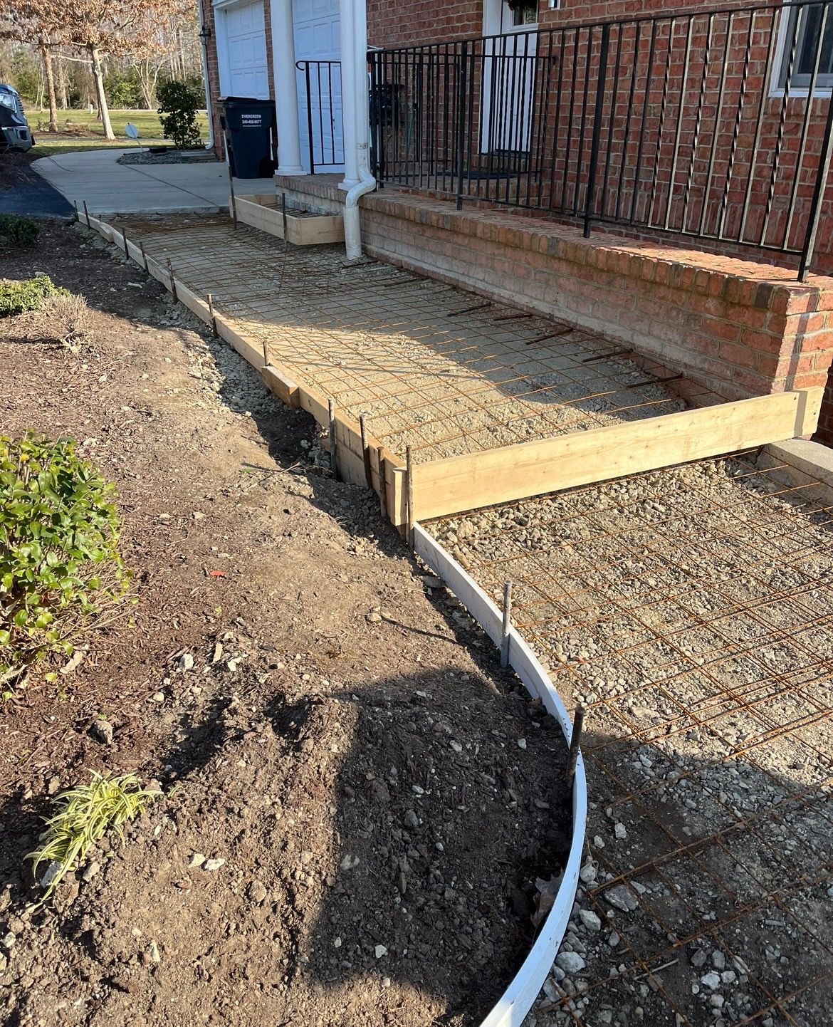 Concrete Project: A walkway construction project, featuring wooden forms and a curved plastic landscape border.