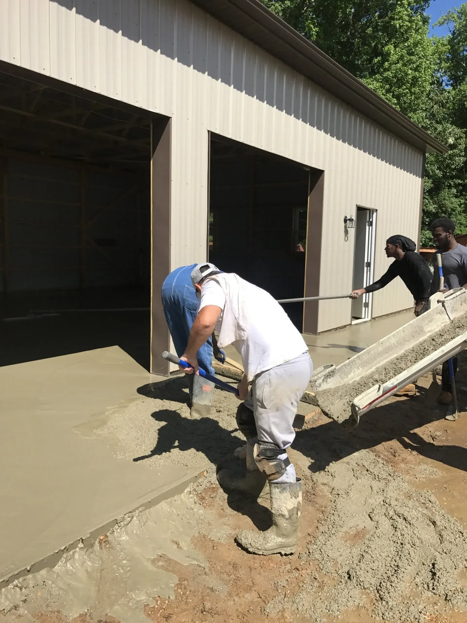 Workers pour& smooth concrete for a driveway outside a metal garage building for a commercial project in Calvert County.