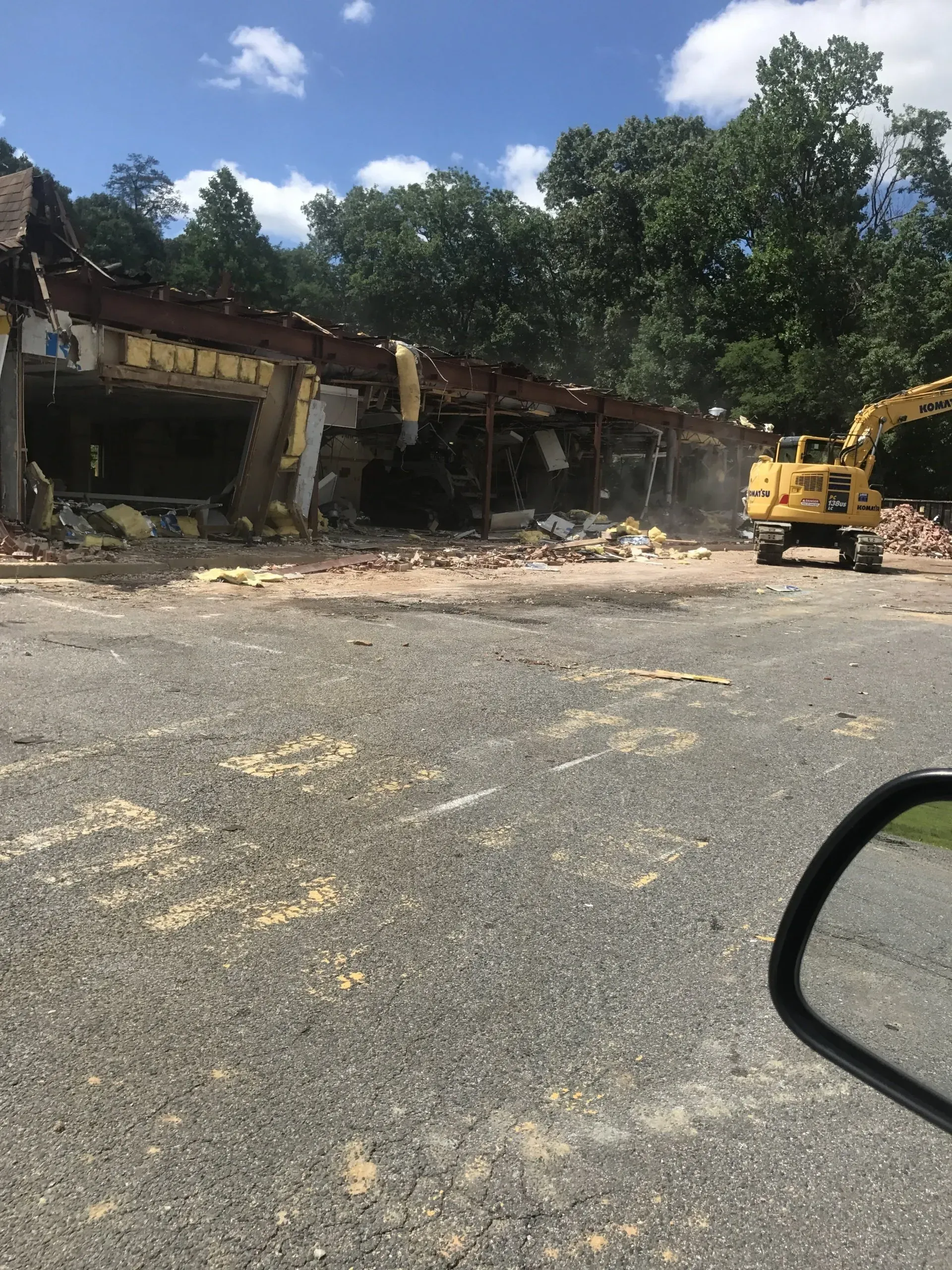 A yellow excavator demolishes a single-story commercial building in Southern MD.