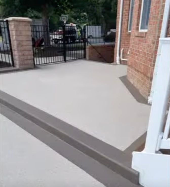A concrete patio in St. Mary's County with light gray flooring and dark brown borders, set against a brick building .