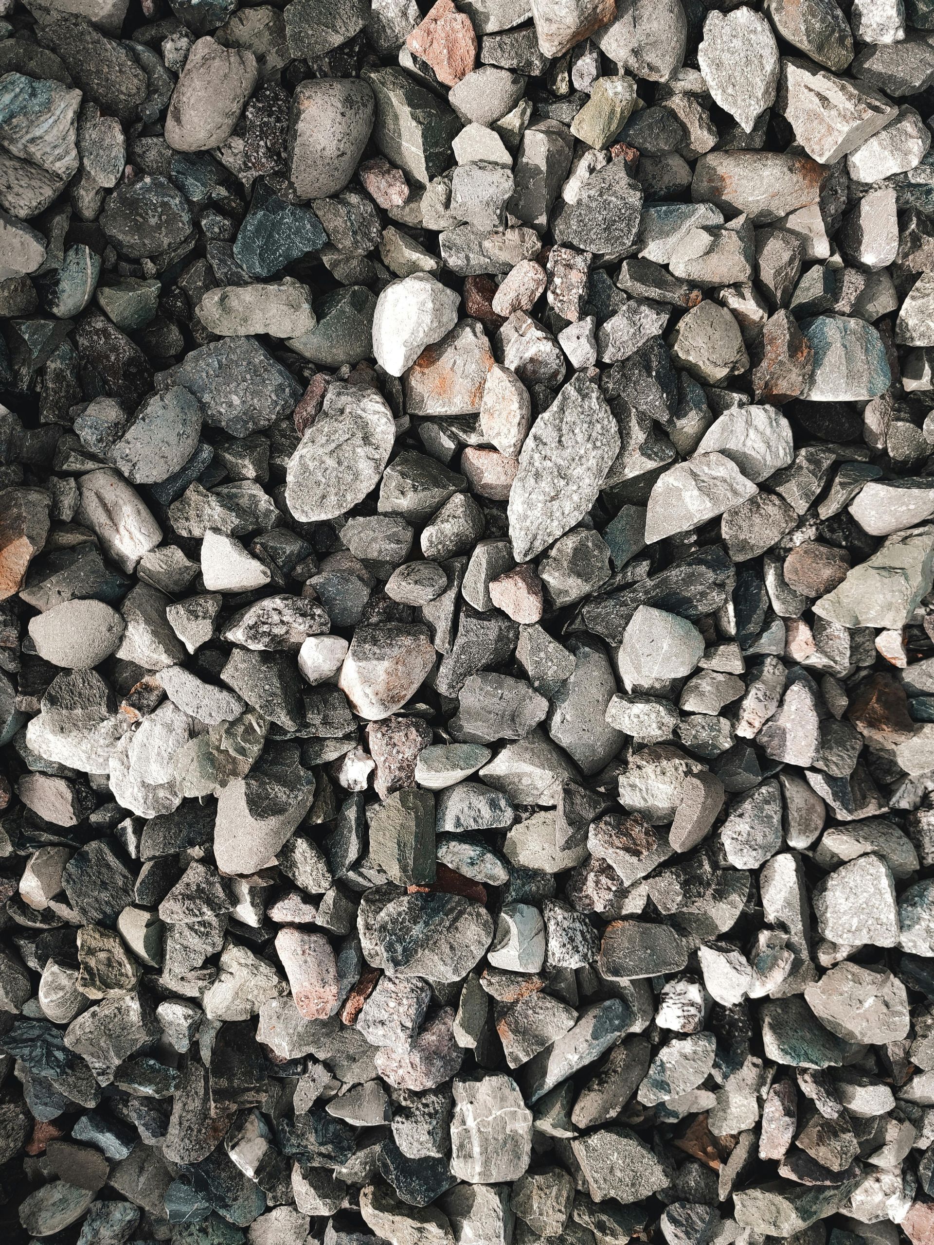 A dense texture of coarse, angular grey and white crushed stone or gravel.