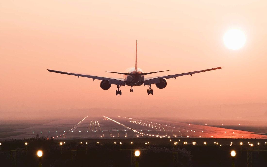 A Tailwind overnight cargo airplane is taking off from an airport runway at sunset.