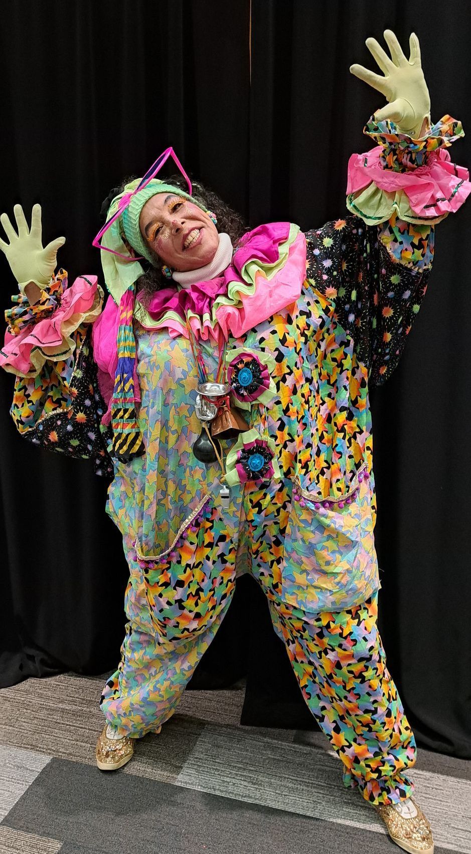 A woman in a clown costume is standing in front of a black curtain at a live event in Calgary, Alberta