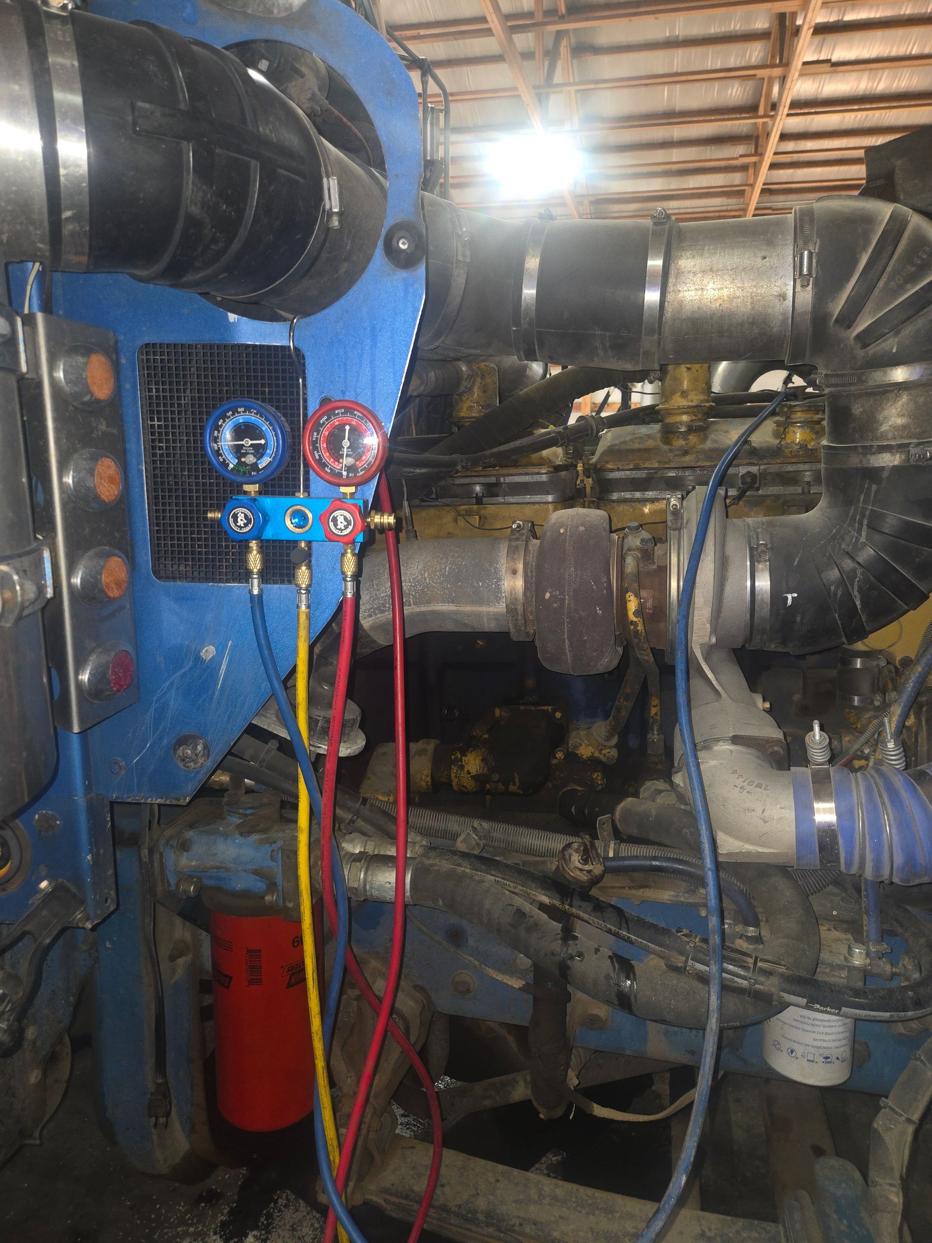 Engine being worked on in a garage. Car frame in background. Chains suspending the engine.