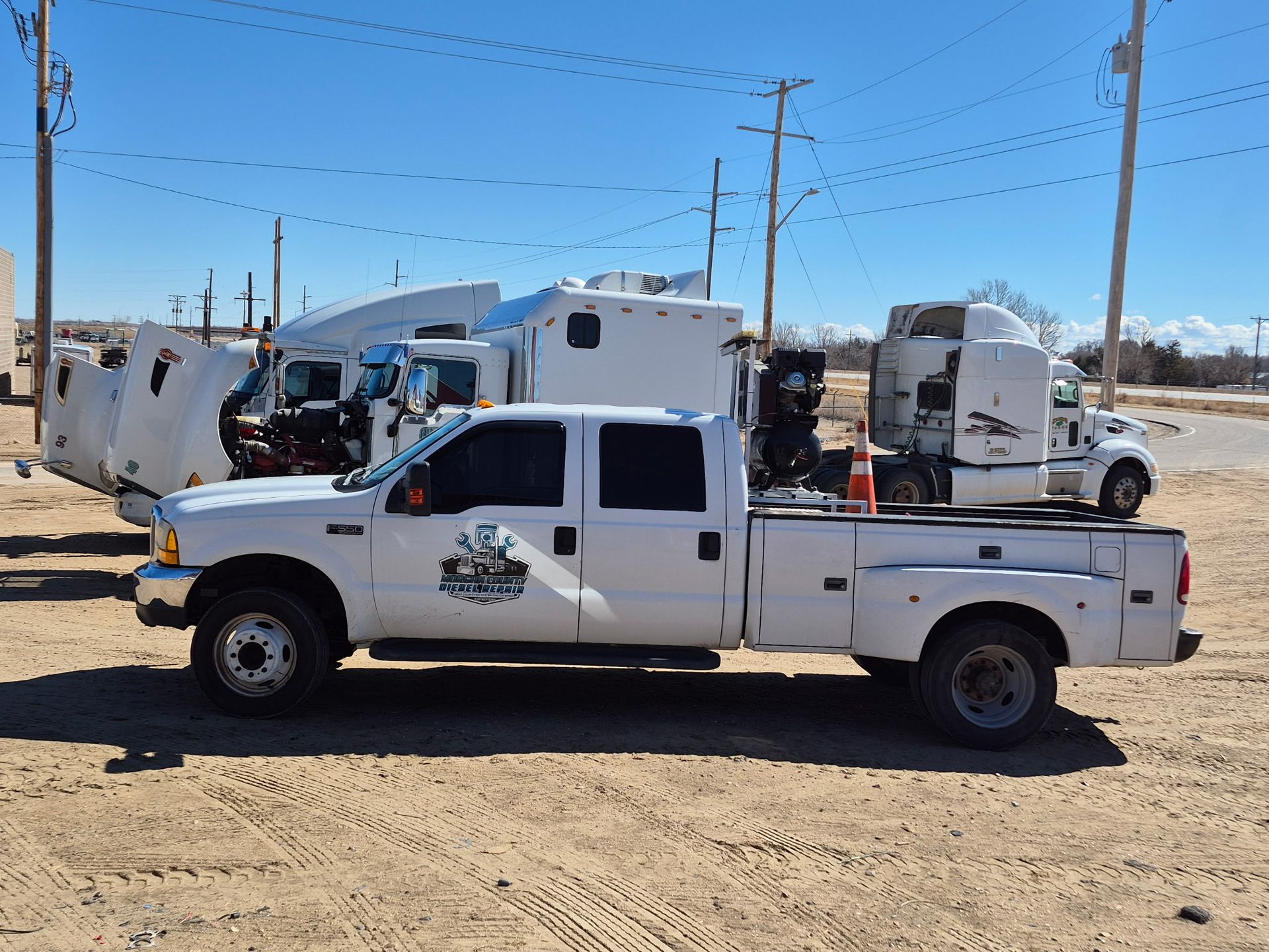 A semi-truck lifted on a hydraulic jack in a repair shop.