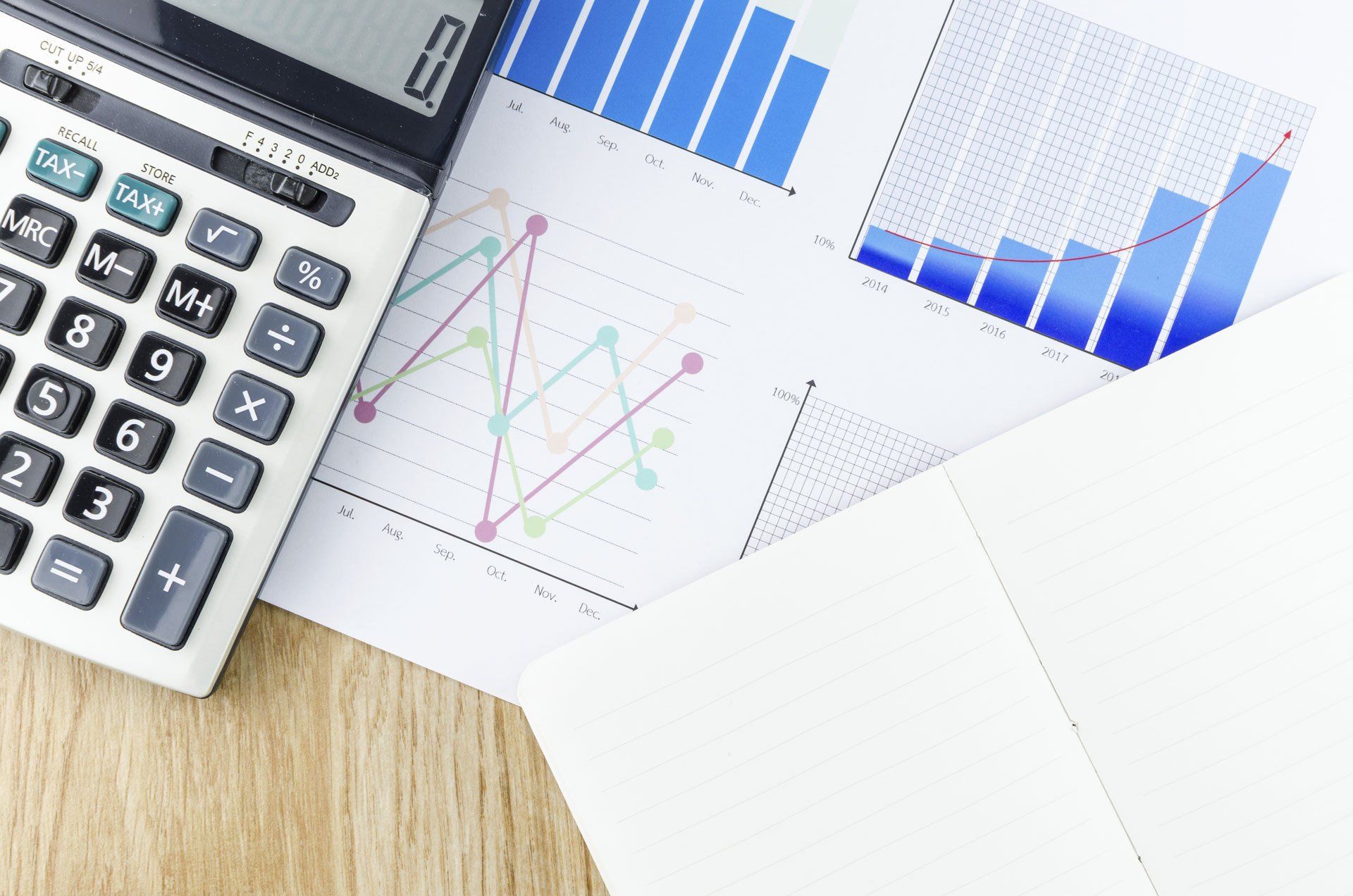 CPA desk with a calculator, graph documents, and journal